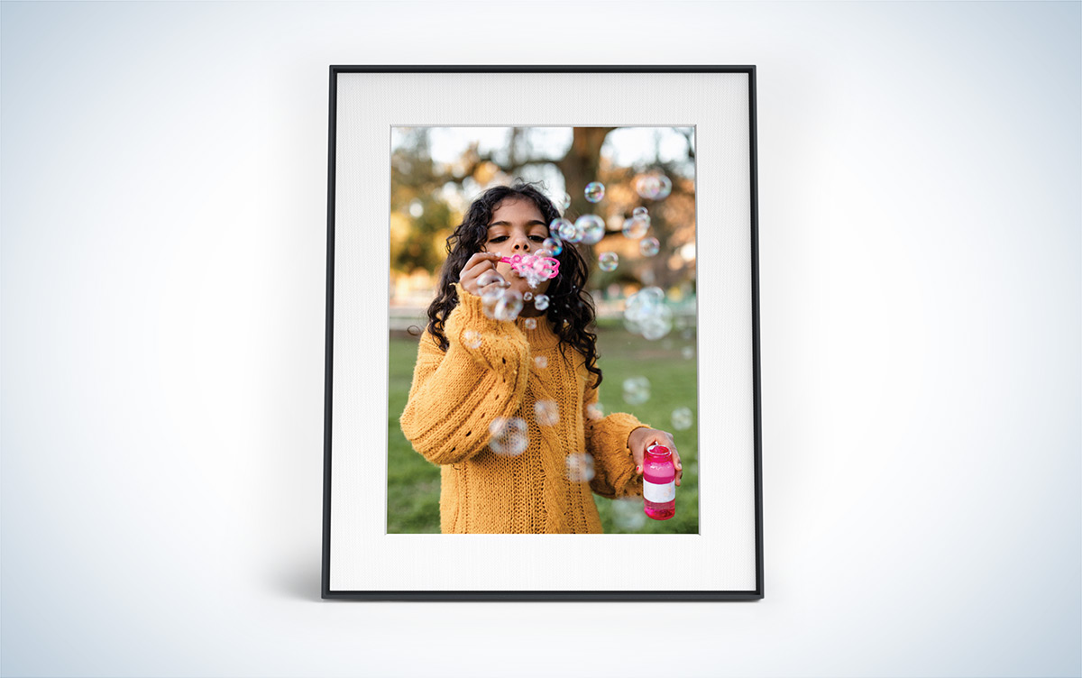 Aura Walden digital picture frame with a photo of a young girl blowing bubbles inside a black frame with a white background.