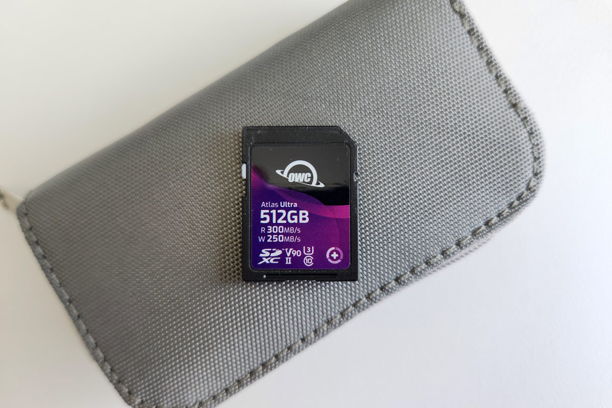 OWC Atlas Ultra SDXC 512GB memory card for cameras on a gray pouch resting on a white table