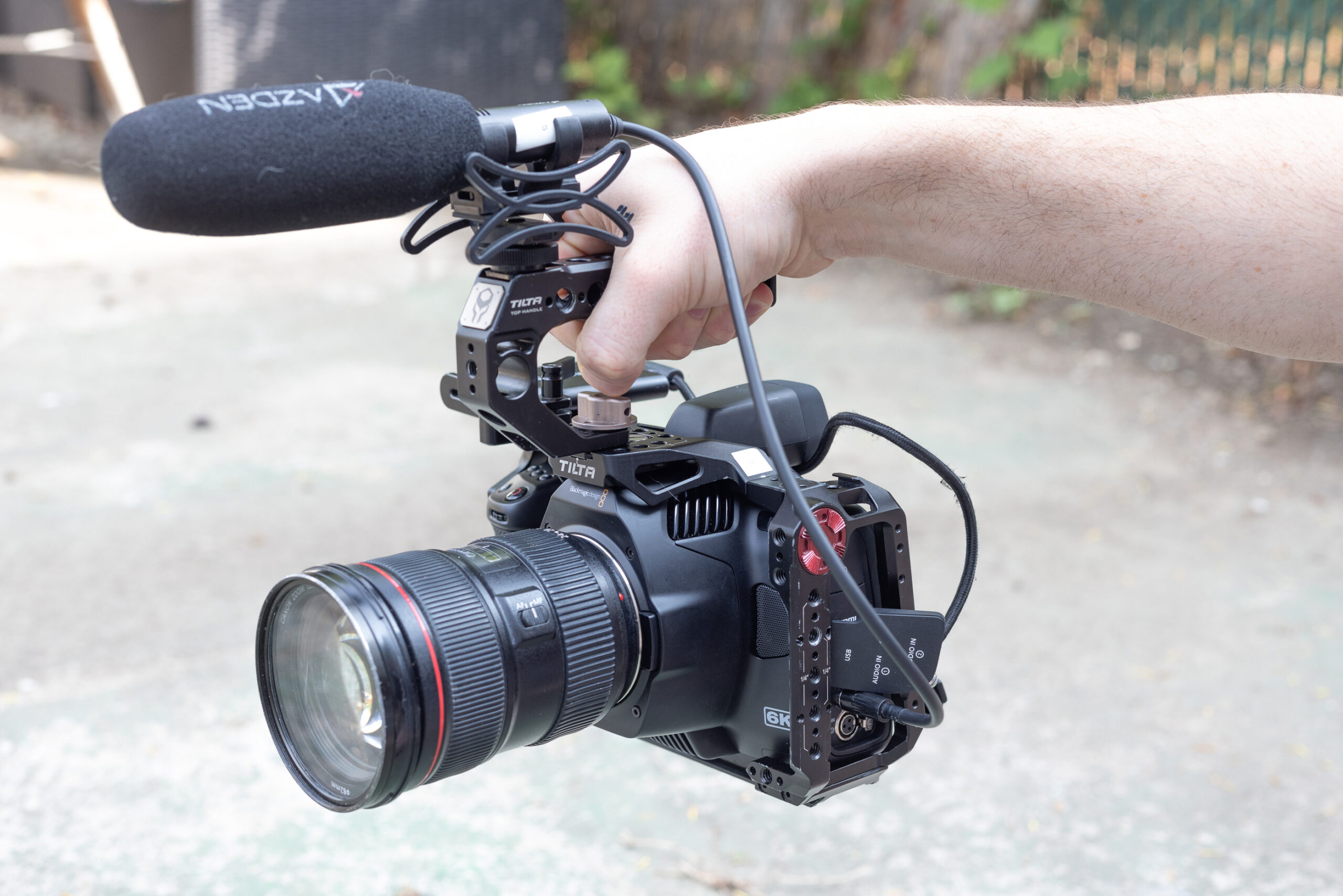 A hand holding the Blackmagic Pocket Cinema Camera 6K G2 in a cage with a mic.