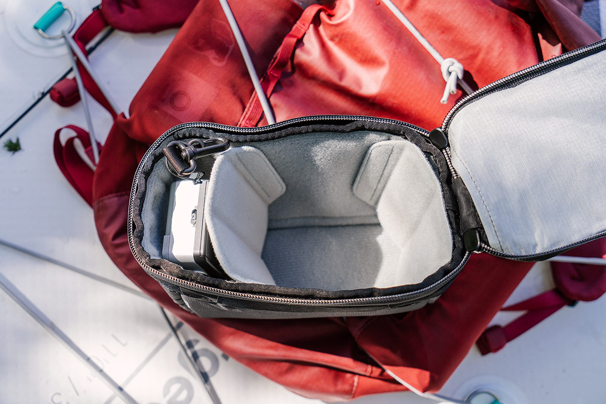 An X-Small Camera Cube V2 sits open on a red bag.